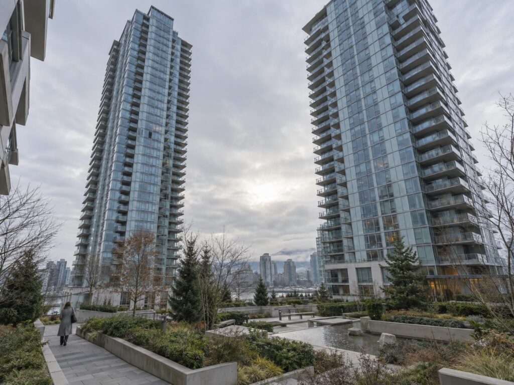 Two contemporary glass condominium towers in Toronto viewed from a landscaped courtyard on an overcast morning