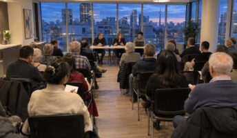 Condominium owners seated in rows at an annual general meeting in a bright building party room, with three directors at a table at the front