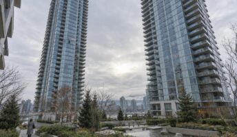 Two contemporary glass condominium towers in Toronto viewed from a landscaped courtyard on an overcast morning