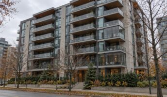 A mid-rise Toronto condominium building seen from the street, with rows of balconies where some have been enclosed in glass and the rest are open