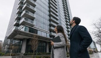 Two condo board directors reviewing a document folder outside a Toronto high-rise while switching property management companies.